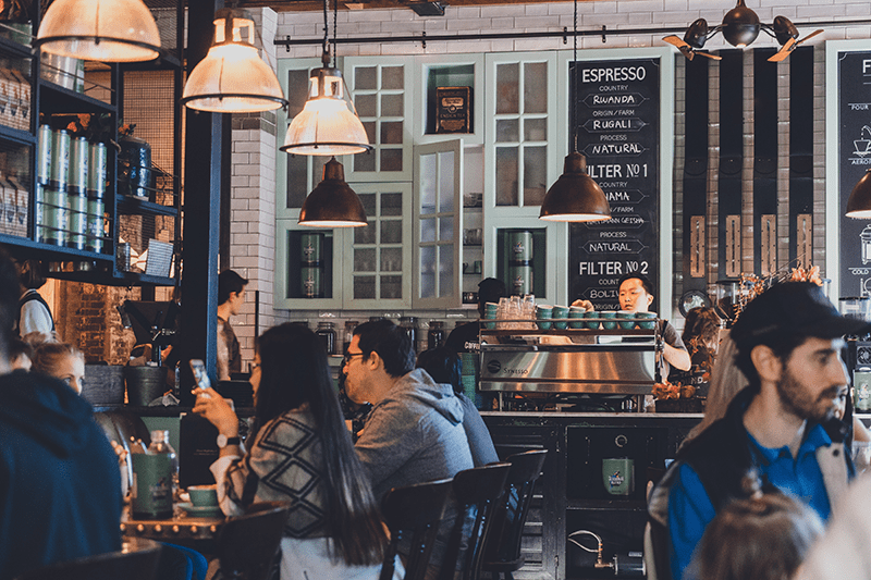 A group of people sitting at tables in a coffee shop.