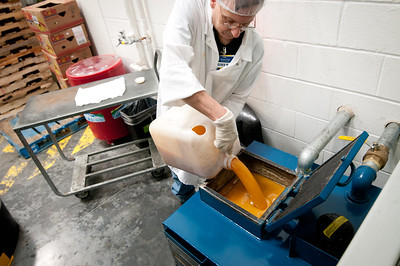 A man in a white overalls pouring grease into a container