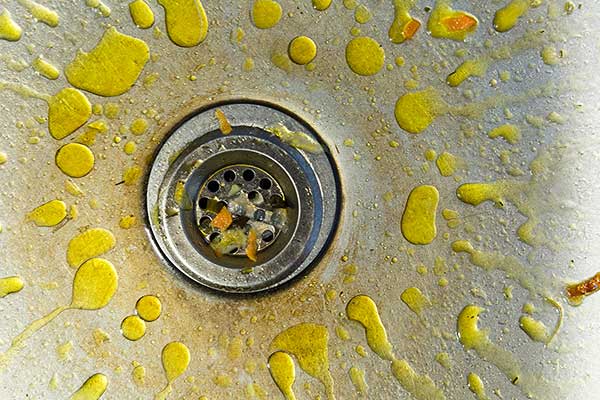 A kitchen sink with yellow splashes of grease on it.